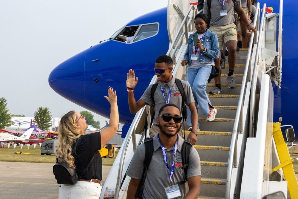 Photo of Tuskegee NEXT students walking down air stairs at EAA AirVenture and giving a  Southwest Employee a high-five.jpg